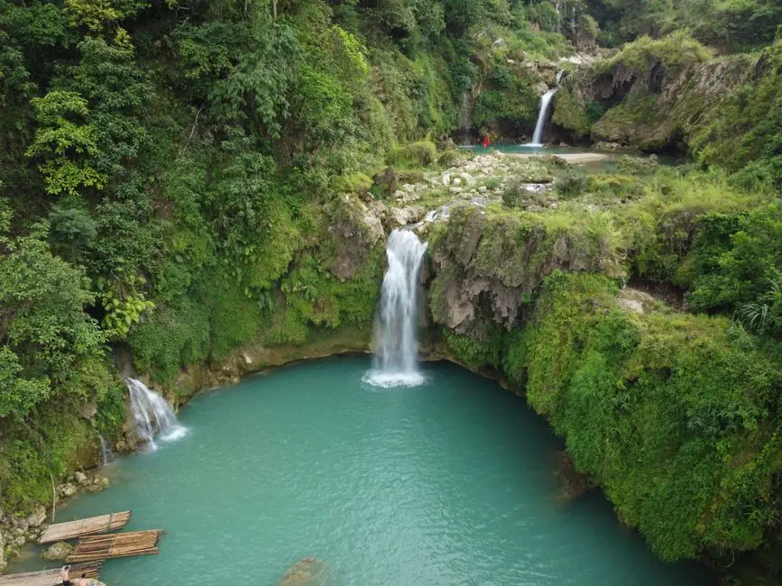 Suasana Air Terjun Aek Martua dengan kolam alami hijau toska dan pepohonan rimbun di sekitarnya